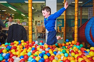 Soft Play boy jumping into ball pit