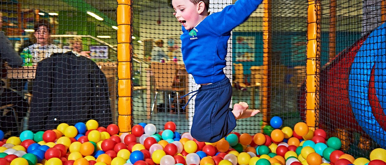 Soft Play boy jumping into ball pit